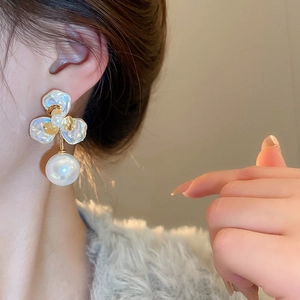 Close-up of gold petal pearl earrings worn by model showing elegant floral texture