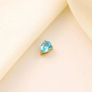 Close-up of sky blue waterdrop zircon pendant with gold base on beige satin fabric