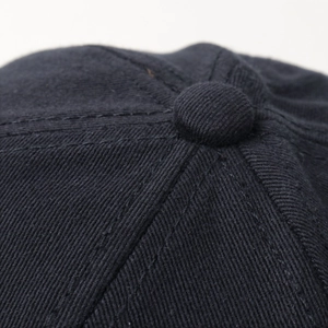 Close-up of black cotton twill baseball cap crown with stitched seams and top button