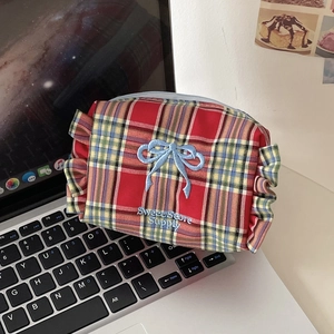 Detail of red plaid cosmetic bag with blue bow embroidery on a laptop keyboard