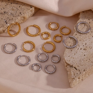Classic stainless steel hoop earrings in gold and silver colors on elegant silk background