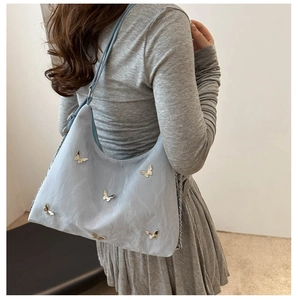 Detail of light blue hobo bag with silver butterfly charms and micro-wrinkled texture