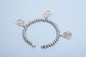 Macro shot of silver ball bead bracelet featuring three intricate Hamsa hand charms