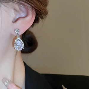 Detailed view of silver teardrop earrings with pear-cut crystals on a female model
