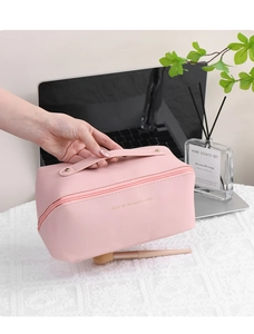 Pink PU leather makeup bag with gold lettering shown in a home office setting