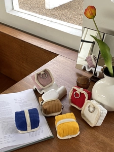 Quilted fabric storage pouches for earphones shown in various colors on a wooden table