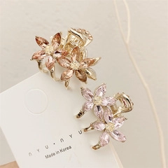 Detailed view of metal flower hair claws set with crystals on a white card display