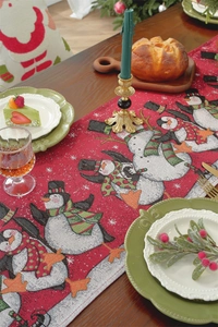 Detail of red Christmas table runner with jacquard penguin pattern on wooden surface