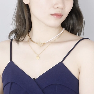 Double-layered gold heart pendant necklace with artificial pearls on elegant female model