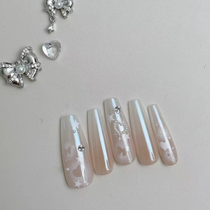 Macro view of coffin press-on nails with butterfly prints, pearls, and cat eye effect