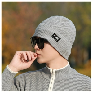 Detailed knit texture of light gray winter beanie featuring black rectangle logo patch
