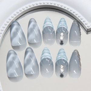 Blue marble press-on nails with 3D wave lines and rhinestone accents on mirror tray