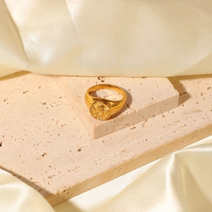 Close-up of vintage gold angel relief ring on beige stone with champagne satin fabric