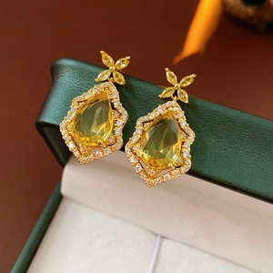 Detailed macro view of golden teardrop earrings with crystals and clover design
