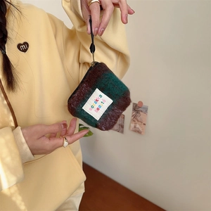Close-up of plush checkered mini pouch with colorful embroidery and black zipper