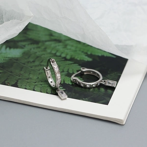 Close-up of S925 silver star hoop earrings with clear zircon pendants on floral paper