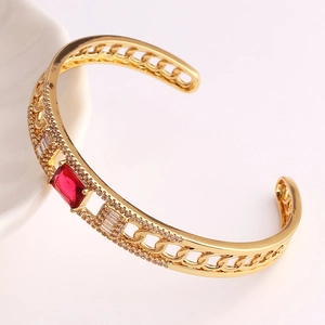 Golden open bangle with a rectangular red gemstone and clear cubic zirconia chain links