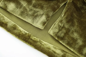 Detailed close-up of olive green velvet fabric with soft texture and refined stitching