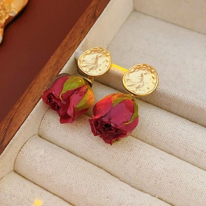 Détail de boucles d'oreilles roses rouges vintage avec clous dorés sur boîte en tissu