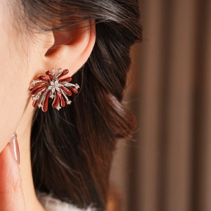 Gros plan de boucles d'oreilles fleurs en zircon avec émail rouge porté par un modèle