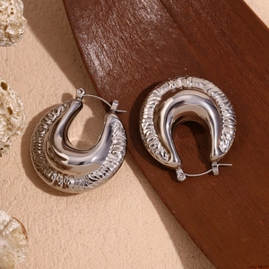 Detail of silver U-shaped hoop earrings with embossed wavy texture and mirror polish