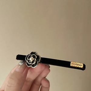 Detail of camellia hair clip with black velvet, pearl center and gold Lovedays metal tag