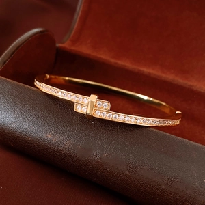 Macro detail of 18K gold plated bangle featuring a cross buckle and micro-set cubic zirconia