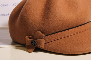 Close-up of brown wool newsboy cap featuring a side bow and shimmering black rhinestones