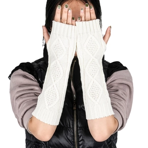 Close-up of cream knit arm warmers featuring classic diamond cable patterns and thumb holes