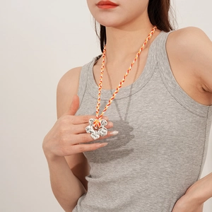 Detail of silver handmade flower pendant on a colorful woven cord necklace for women