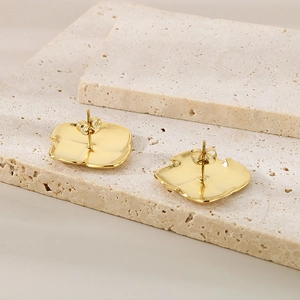 Detail shot of golden irregular geometric petal earrings on natural stone background