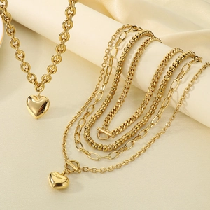 Détail d'un collier doré multicouche avec pendentif cœur 3D et maillons mélangés