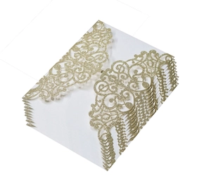 Detail of laser-cut wedding invitation with champagne gold glitter and floral patterns