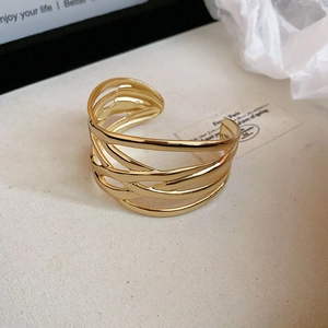 Detailed close-up of a gold hollow layered bangle on a minimal elegant background