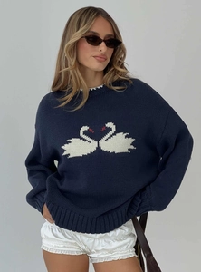 Detailed close-up of dark blue knit sweater with white swan pattern and soft texture