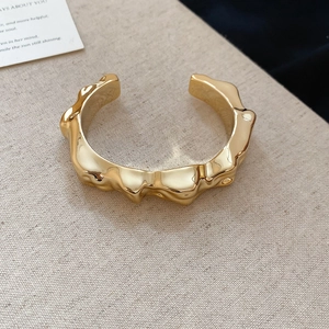 Detailed view of gold irregular wavy cuff bracelet with a high-shine polished metallic finish