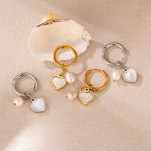Detailed close-up of heart-shaped shell and pearl dangle earrings in gold and silver