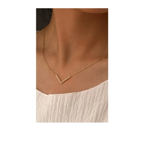 Close-up of a minimalist gold V-shaped pendant necklace with pavé micro-zirconia on a model