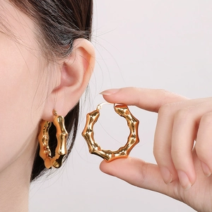Close-up of golden bamboo-joint texture hoop earrings with polished titanium steel finish