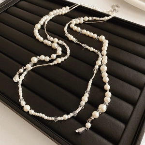 Vue détaillée d'un collier de perles vintage avec pendentif goutte sur plateau noir
