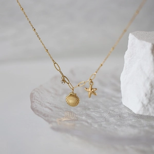 Gold starfish and seashell pendant necklace with zircon on elegant glass ripple surface