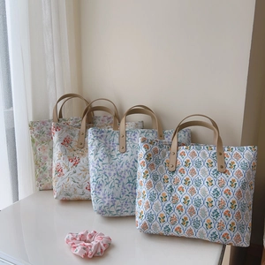 Détail de sacs fourre-tout en toile florale avec anses en cuir et chouchou assorti