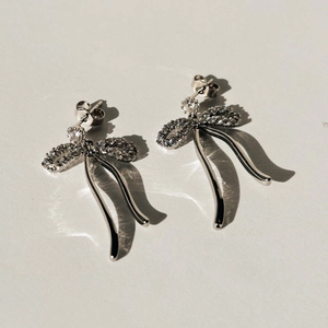 Orecchini a fiocco in argento con strass scintillanti e catena a serpente su sfondo bianco