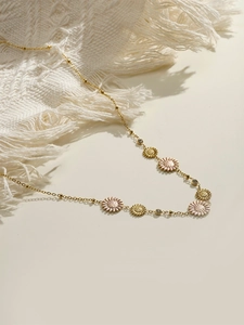 Detailed macro view of 18K gold plated daisy charms and diamonds on a chain necklace