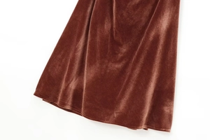 Detailed macro view of terracotta velvet fabric with elegant draped pleats on a midi dress