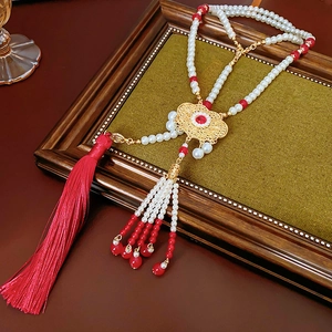Detailed close-up of a Phoenix lock necklace with pearls, red beads, and silk tassels