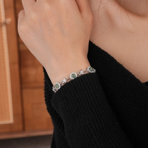 Détail d'un bracelet fleur en argent avec pierre verte et zircons au poignet d'un mannequin