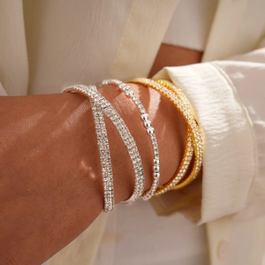 Luxurious layered rhinestone beaded bracelets in gold and silver finishes on a wrist
