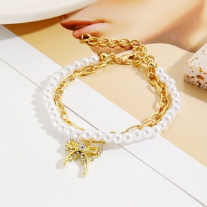 Detail of layered baroque pearl bracelet with golden bow pendant and sparkling crystals
