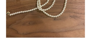 Flat lay of vintage multi-layer pearl necklace with golden heart clasp on dark wood